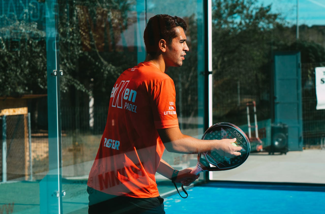 featured-portfolio-03 A focused young man practices padel tennis outdoors on a sunny day, showcasing skill and concentration.