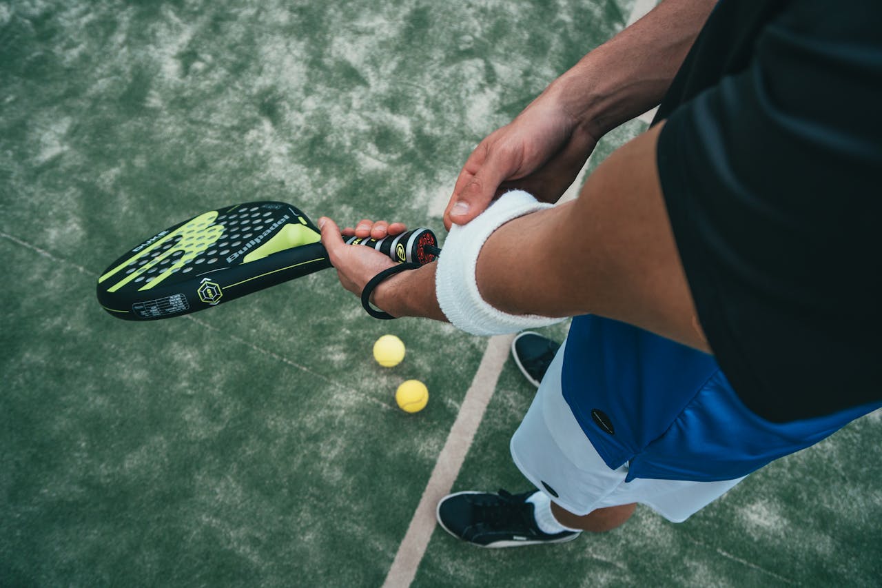 my-work-04 Close-up of a male padel player adjusting wristband on a court. Sports action focused.